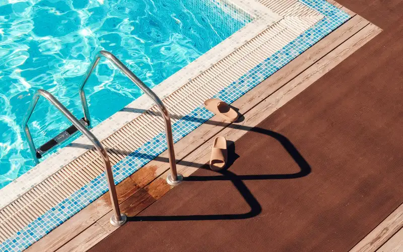 A clean swimming pool with a ladder and a wooden deck