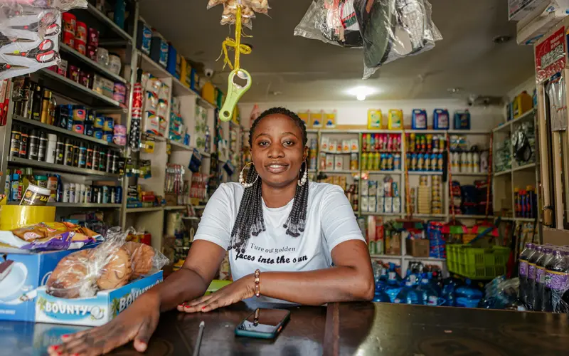 A shop owner smiling behind the counter of her small store