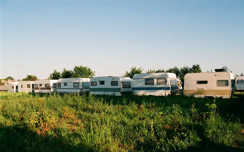 A row of travel trailers parked in a grassy lot