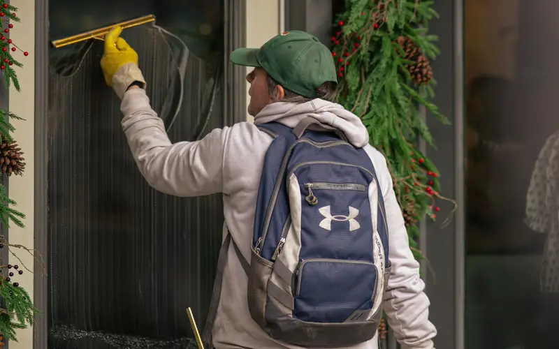 A window cleaner using a squeegee on a storefront door